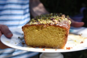 Husband holds a super moist and zesty grapefruit olive oil cake decorated with grapefruit-flavoured icing and salted roasted pistachios, a recipe from Cook This Book | More info clicking on the picture